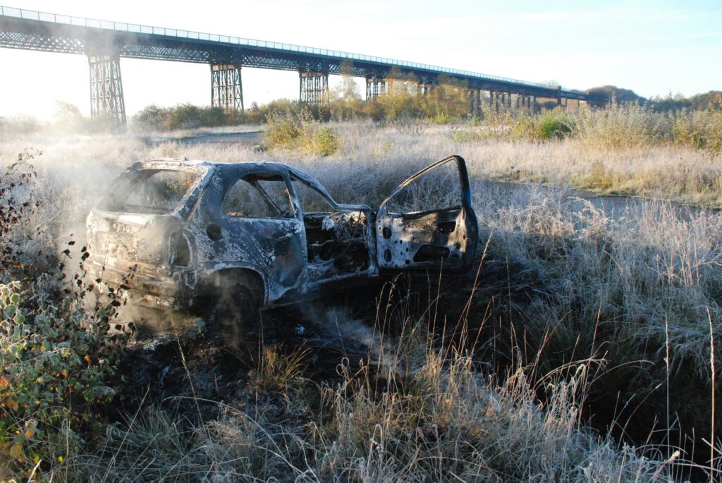 An abandoned car situated in front of the viaduct.