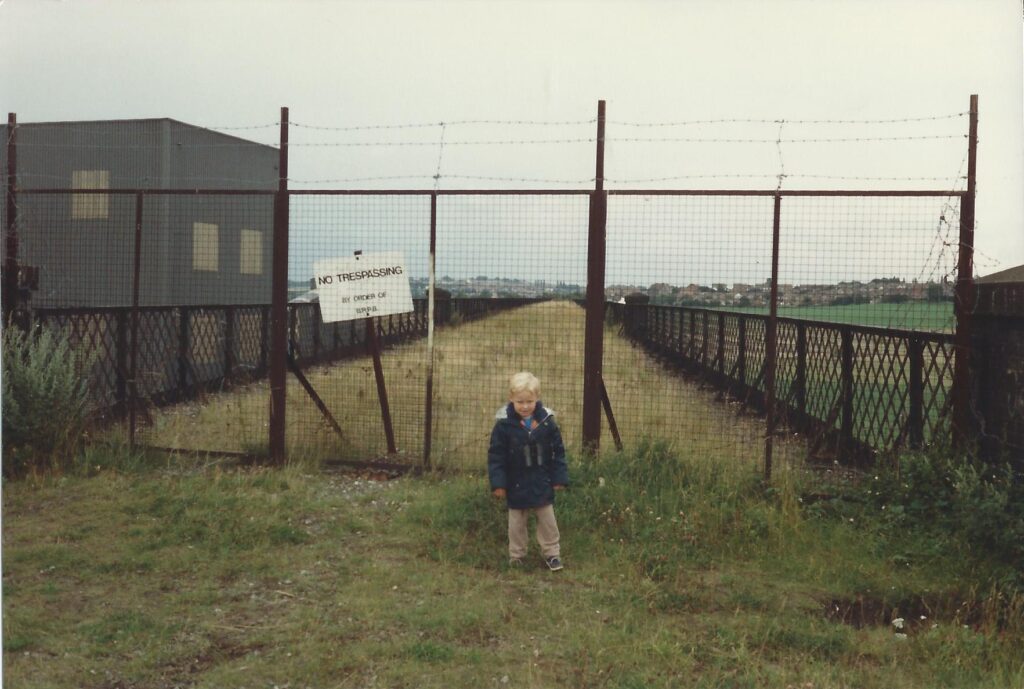 A boy having his picture taken in front of the locked gates of Bennerley Viaduct.