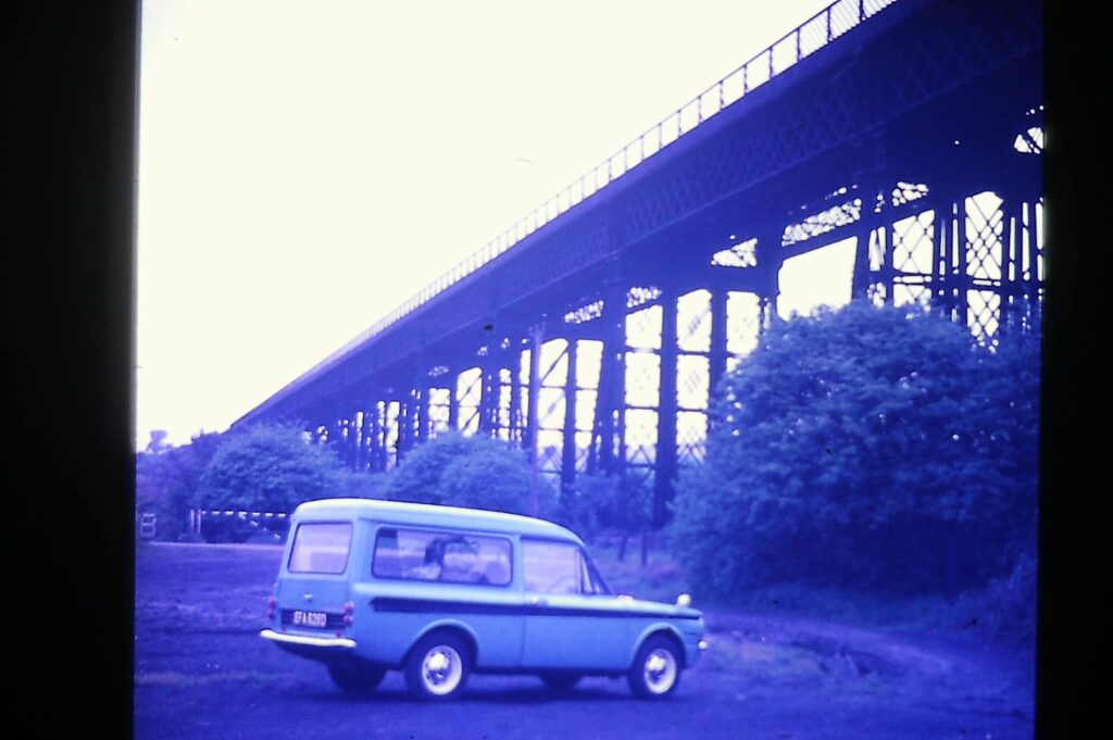 An old photograph of a car parked adjacent to the viaduct.