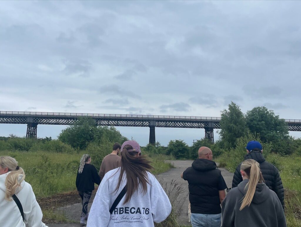 Group Walking Viaduct In Background