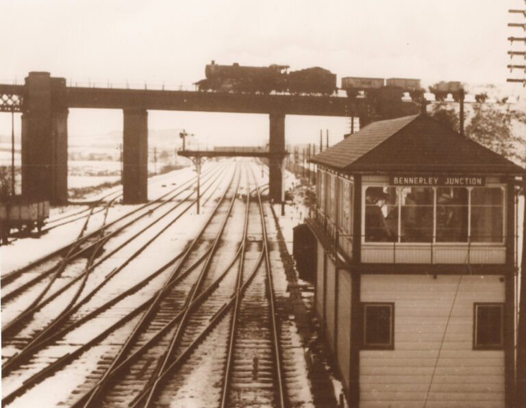 The signal box next to the viaduct with a locomotive travelling across the viaduct.